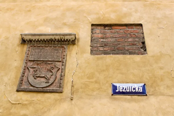 Brasão de armas, fragmento de parede de tijolo e placa de identificação de rua na guerra — Fotografia de Stock