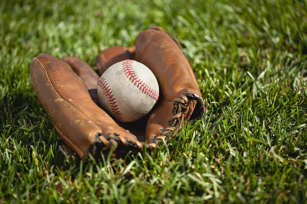 Guante de béisbol vintage con una bola vieja en la hierba — Foto de Stock