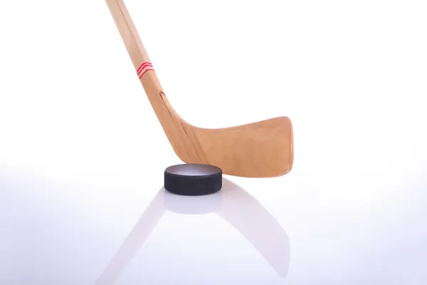 Hockey klubba och puck på reflekterande yta — Stockfoto