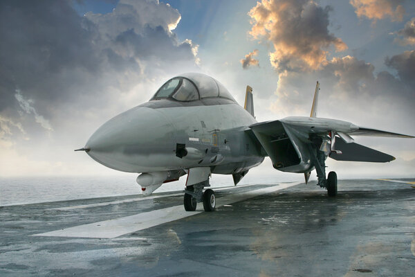 F-14 jet fighter on an aircraft carrier deck beneath dramatic cl