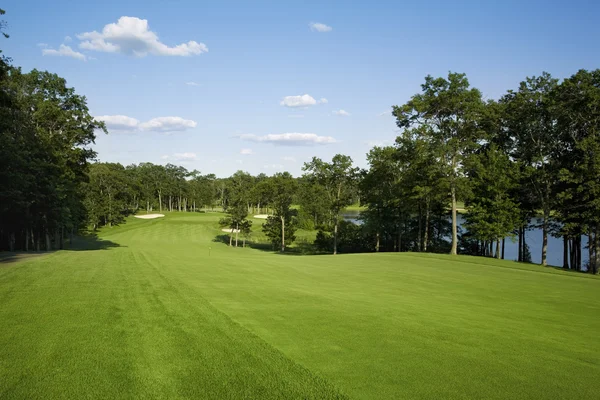 Golf fairway lined with trees near lake — Stock Photo, Image