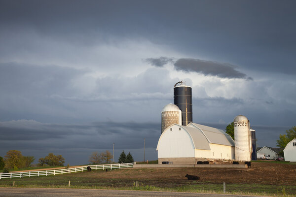 Barn and silos of midwestern farm under stormy skies