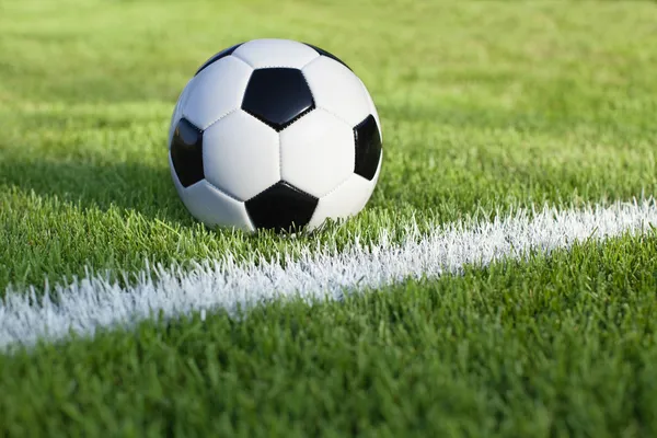 Balón de fútbol se sienta en el campo de hierba con la raya blanca —  Fotos de Stock