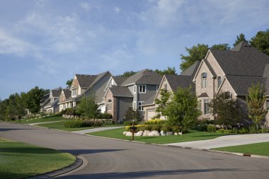 Houses on upscale suburban street in morning sunlight clipart