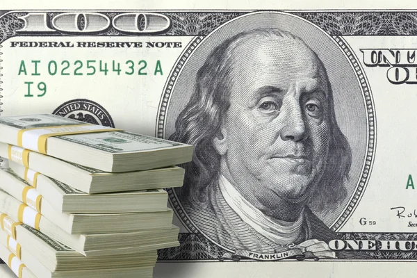 Stack of one hundred dollar bills with a large bill in the backg — Stock Photo, Image