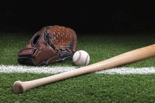 Baseball mit Handschuh und Schläger auf grünem Gras in der Nacht — Stockfoto