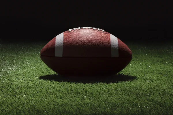 College football on grass field at night with spot lighting — Stock Photo, Image