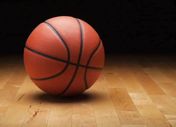 Basketbal met donkere achtergrond op een houten sportschool vloer — Stockfoto