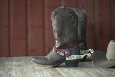 Cowboy boots, spurs and hat on old wood background clipart