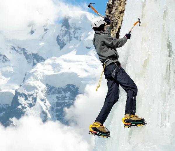 Hombre escalando en la caída de hielo en las montañas de invierno Imagen De Stock
