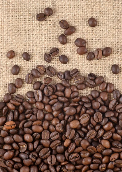 Kávová zrna v pozadí pytloviny — Stock fotografie