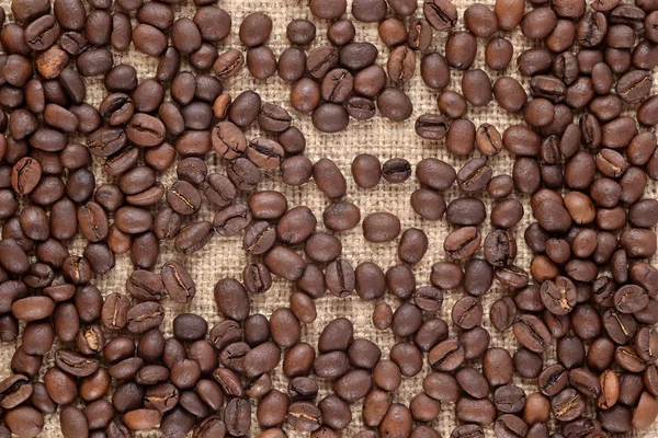 Granos de café en un fondo saqueador — Foto de Stock