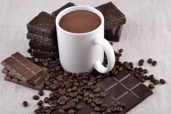 White cup of hot chocolate on coffee beans and chocolate backgro — Stock Photo, Image
