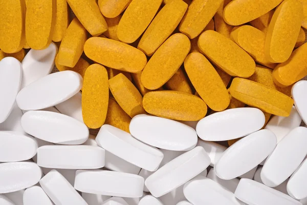 Valkoinen ja keltainen pillereitä tausta — kuvapankkivalokuva