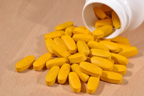 Pílulas amarelas derramar para fora da garrafa — Fotografia de Stock