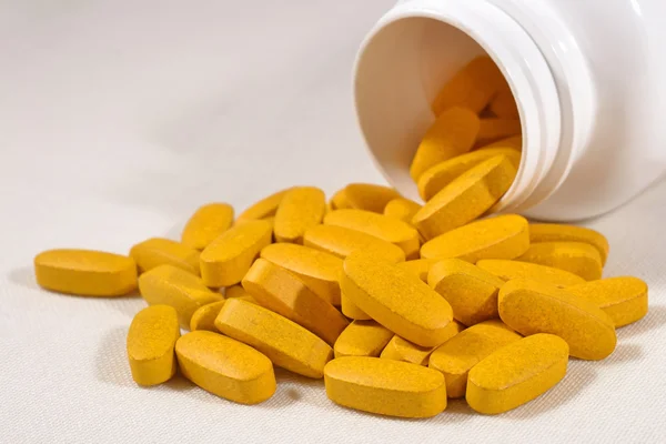 Yellow pills spill out from bottle — Stock Photo, Image