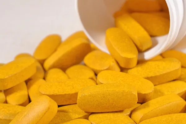 Yellow pills spill out from bottle — Stock Photo, Image