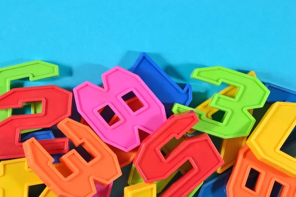 Heap of plastic colored numbers on a blue background — Stock Photo, Image