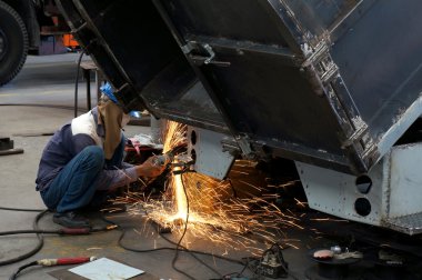 Metal ve kıvılcımlar üreten koruyucu maskeli kaynakçı.