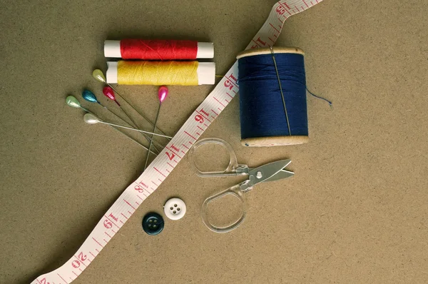 Oude stijl beeld van katoen rollen en andere naaien items op een houten tafel — Stockfoto