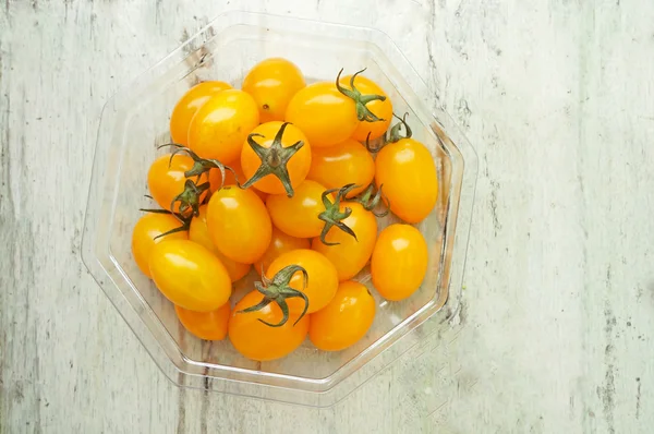 在桌子上的塑料容器中的黄色樱桃西红柿。 — 图库照片