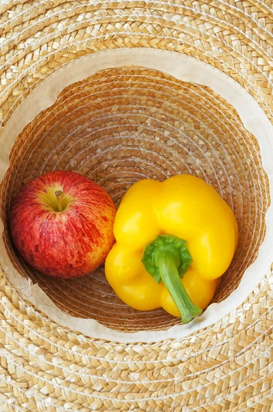 Freshly harvested yellow pepper bell and apple in hat — Stock Photo, Image