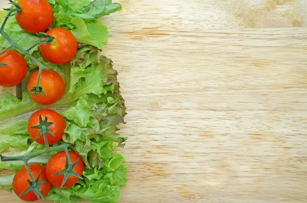 Verse tomaten en sla op houten achtergrond — Stockfoto