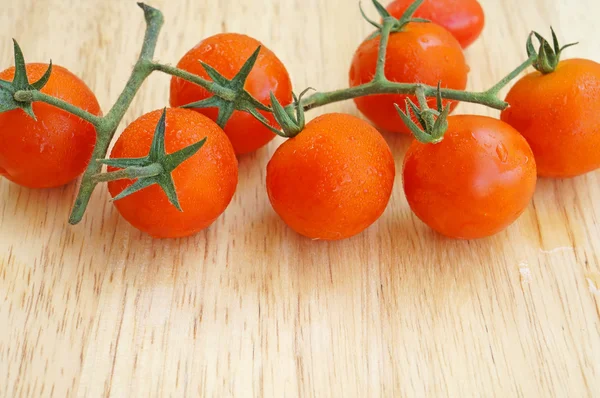 Branch of red ripe cherry tomatoes on a wooden board — Stock Photo, Image