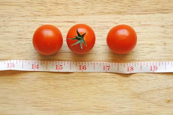 Tomates cherry con cinta métrica sobre fondo de madera (concepto de dieta ) —  Fotos de Stock