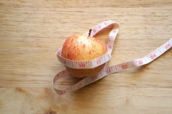 Envoltura de manzana con cinta métrica en mesa de madera —  Fotos de Stock