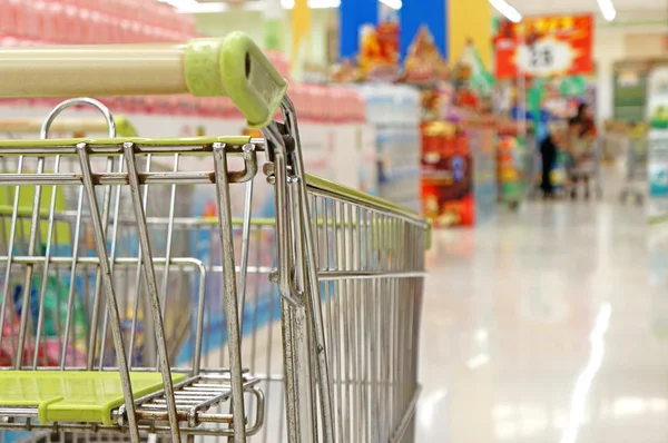 Leerer Einkaufswagen mit Supermarkt als Hintergrund — Stockfoto