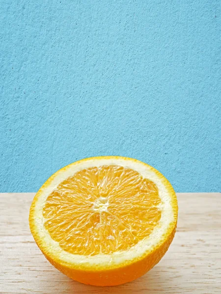 Нарезанные оранжевые фрукты с голубой стеной — стоковое фото