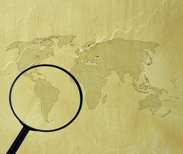 Weltkarte auf Zementwand mit Lupe — Stockfoto