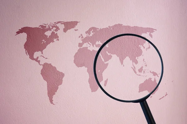 Карта мира на цементной стене с лупой — стоковое фото