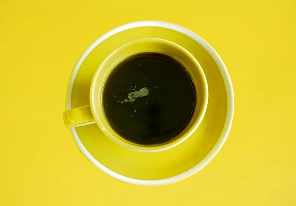 Vista superior de la taza de café negro sobre fondo amarillo — Foto de Stock