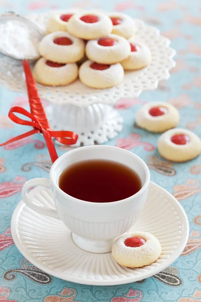 Cup of hot tea and homemade almond cookies filled with jam