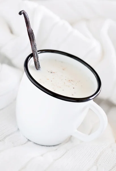 Mug of hot milk with vanilla and spices on a white knitted blanket — Stock Photo, Image