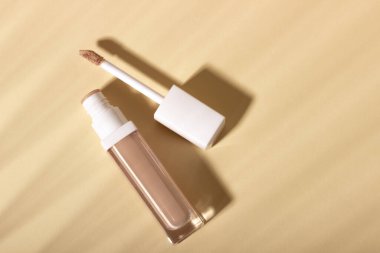 Gölgeli bir arka planda gizleyici krem. Bej arkaplanda kopya alanı olan yüz düzeltici. Ürün için boş model