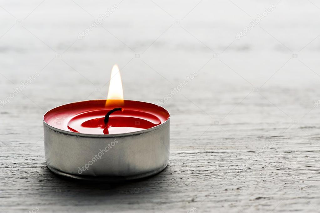 Single burning red tealight candle