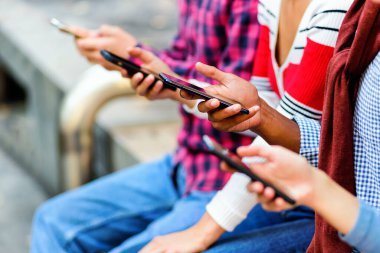 Gündüz vakti pansiyonerlerin üzerinde oturan ve akıllı telefonlar kullanan tanınmayan arkadaşlara yan bakış.