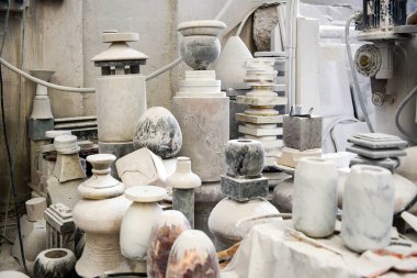 Birçok taş kap ve vazo profesyonel mermer atölyesinde beton duvarlarla bir araya toplanmış.