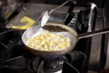 Geleneksel İtalyan Tortellini makarnası et dolgusu ve peynir sosuyla bir tavada pişiriliyor.