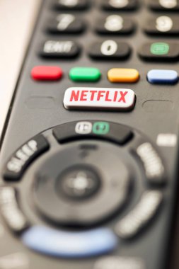 Bir TV uzaktan kumandasındaki Netflix düğmesi bir medya yayın aboneliği ve ev eğlencesi hizmetinin seçici odak kavramını kapatır