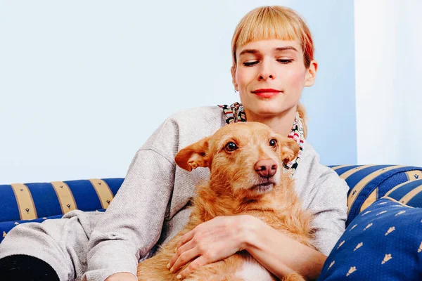 姜汁女坐在沙发上朝下看 与红毛可爱的狗在家里休息 — 图库照片