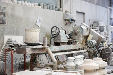 Gri duvarlı hafif mermer atölyesinde üretim makinesinin yanına çeşitli kil yapılar yerleştirildi
