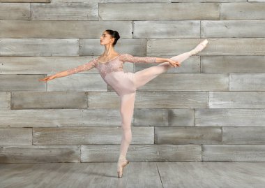 Dans stüdyosundaki prova sırasında parmak uçlarında sivri uçlu ayakkabıyla dengede duran kadın klasik balerin.