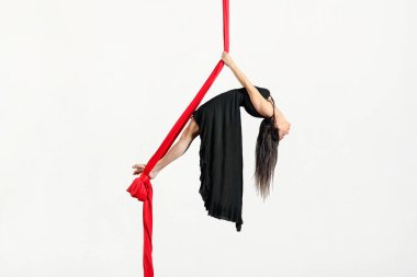 Beyaz arkaplana karşı antrenman sırasında havadaki ipeklerle Fransızca anahtar numarası yapan etkin elbiseli bir kadın.