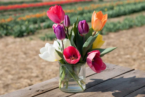Boeket Heldere Kleurrijke Tulpen Geplaatst Glazen Pot Met Water Houten — Stockfoto