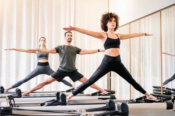 从健康和健康的角度出发 许多人在健身房的改革者床上做着瑜伽的普拉提课 — 图库照片