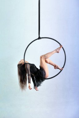 Stüdyoda arka planda hafif ışığa karşı antrenman sırasında ayın üzerinde tekme atan kadın vücut tarafı görüntüsü.